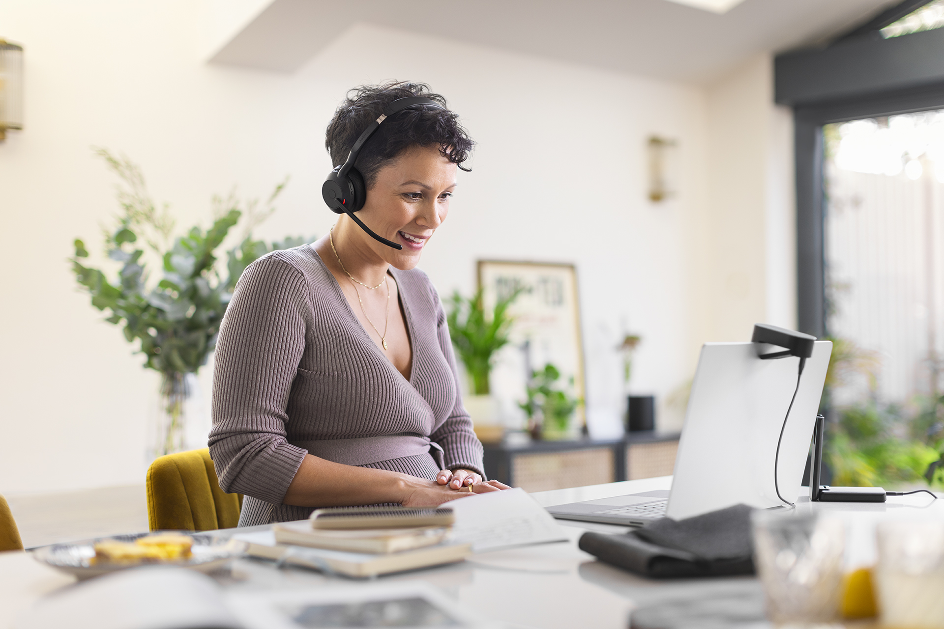 Jabra Evolve2 55 female working at kitchen island talking on a call_ Small