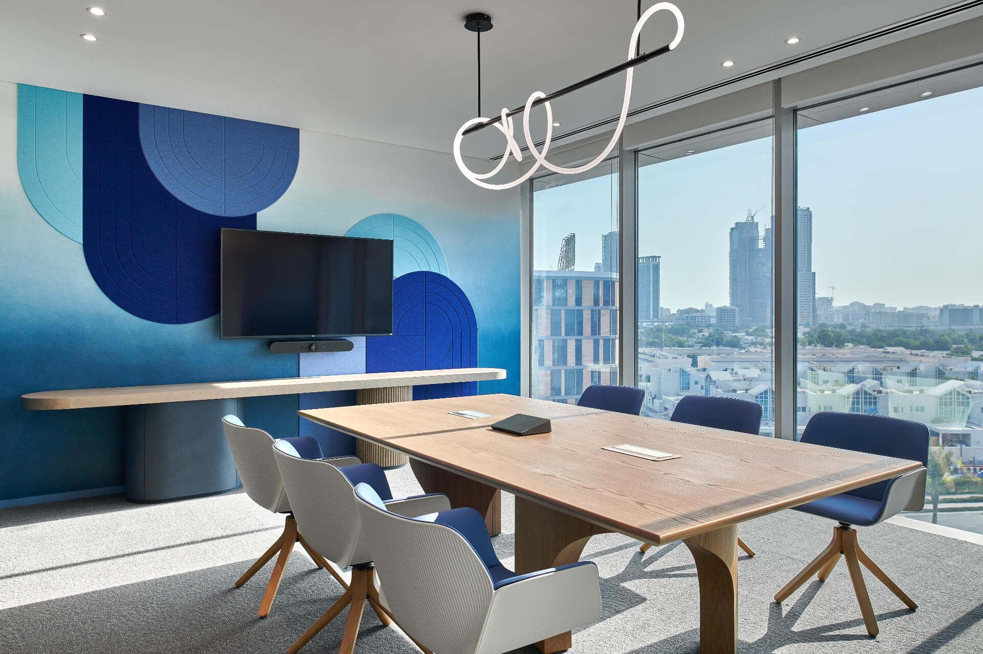 Conference room overlooking cityscape with blue painted wall with geometric shapes.  Source: https://www.summertown.ae/sustainability-hub/