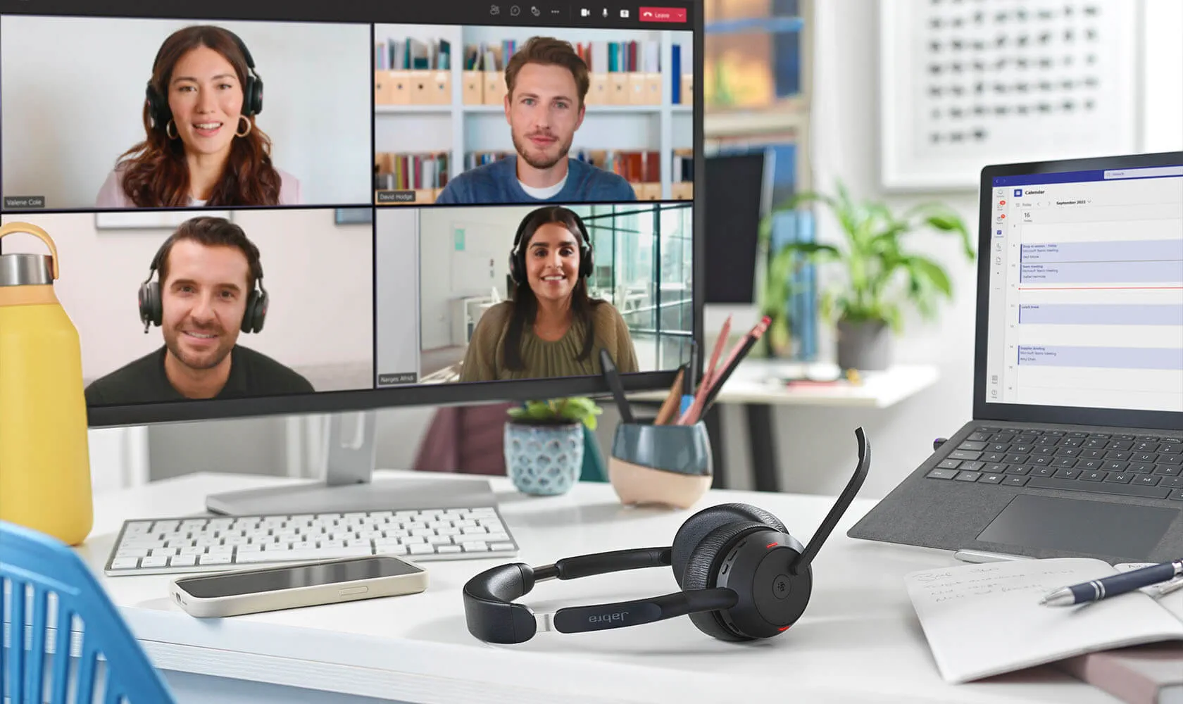 Jabra Evolve2 55 Headset liegt auf einem Schreibtisch neben Laptop und Monitor mit Videokonferenz