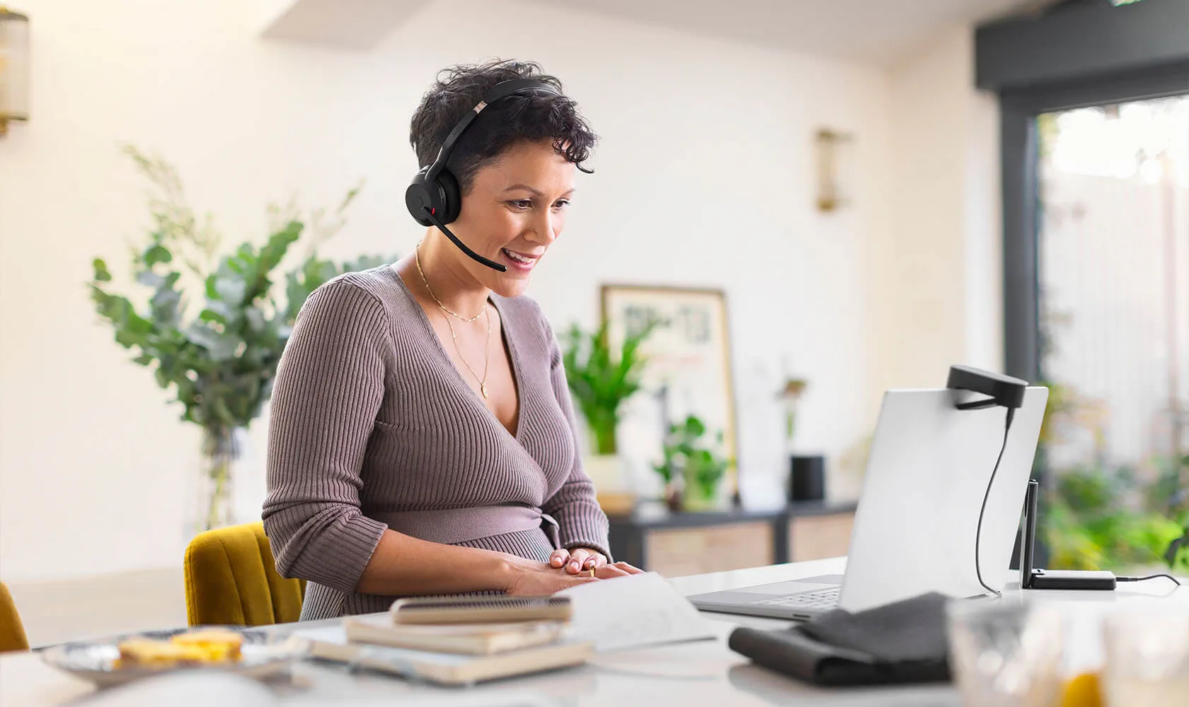 Frau mit Jabra Evolve2 55 Headset im Homeoffice während eines Gesprächs am Laptop