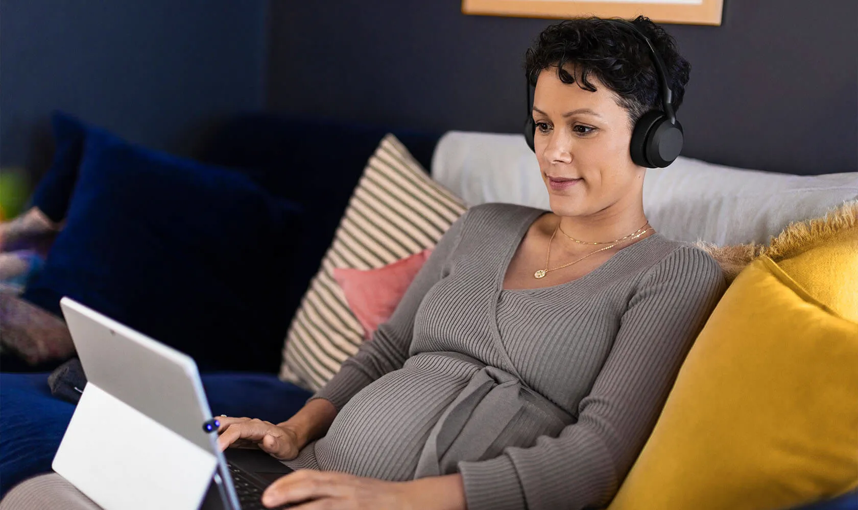 Frau hört mit Jabra Evolve2 55 Headset Musik oder nimmt an einem Call vom Sofa aus teil